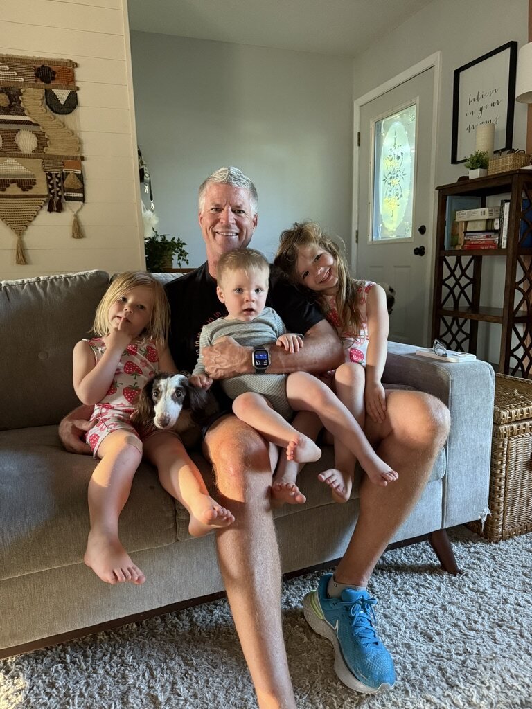 Mark on the couch with three grandchildren and a puppy