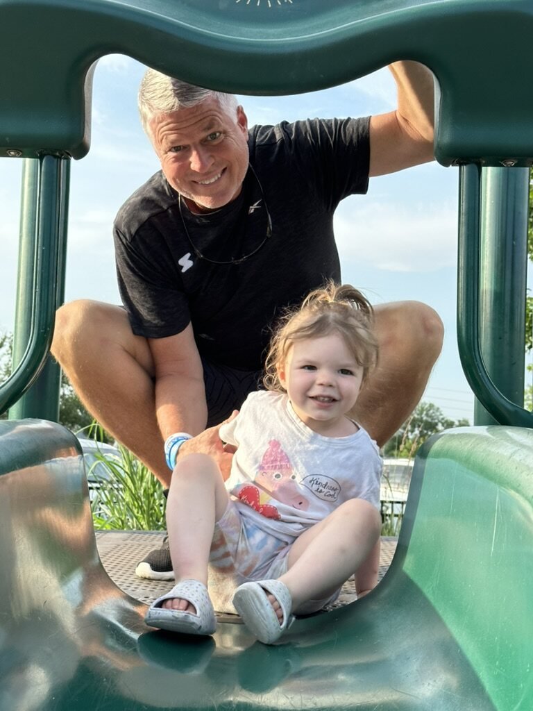 Mark with his granddaughter on the playground slide
